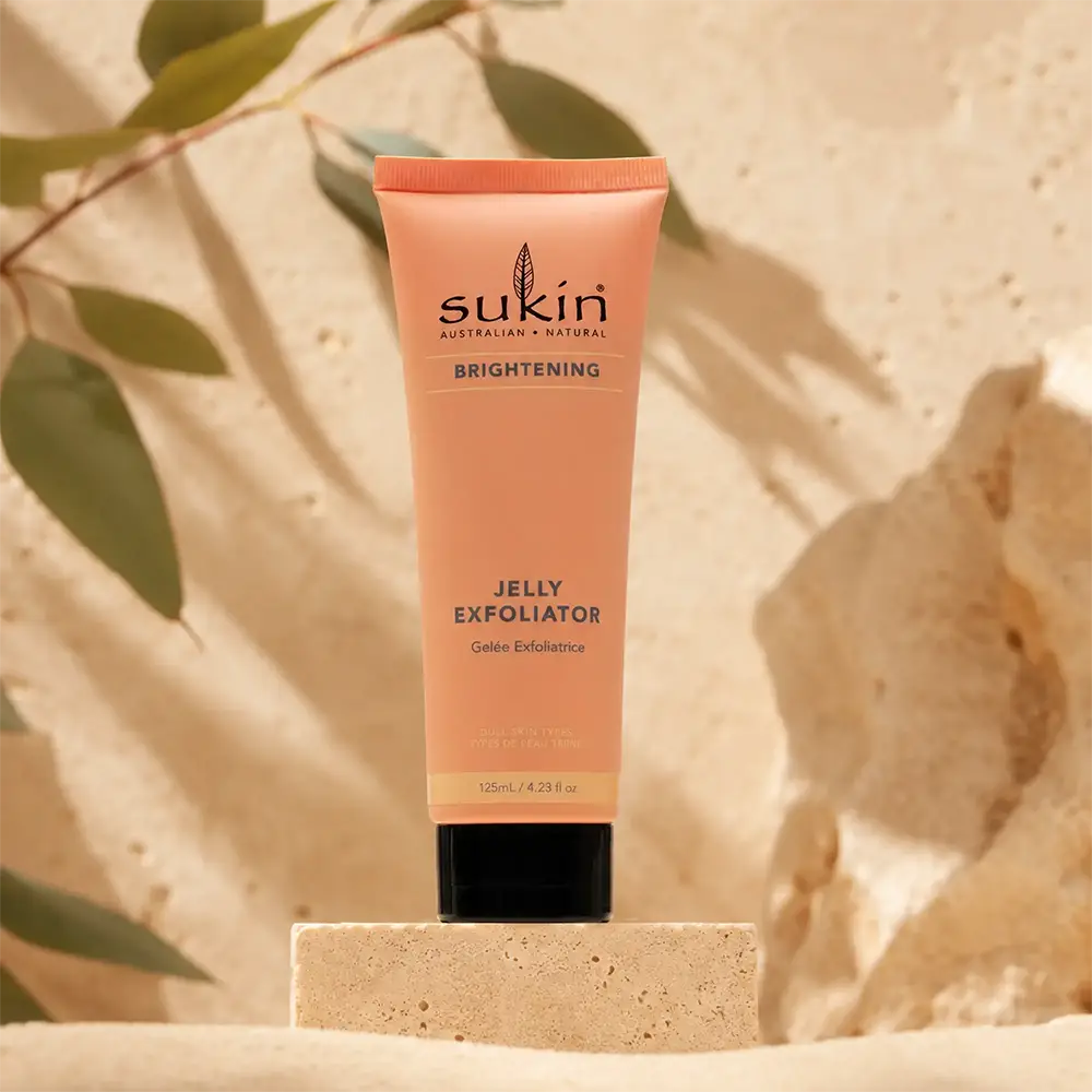 Sukin jelly exfoliator on warm stone with botanical shadows